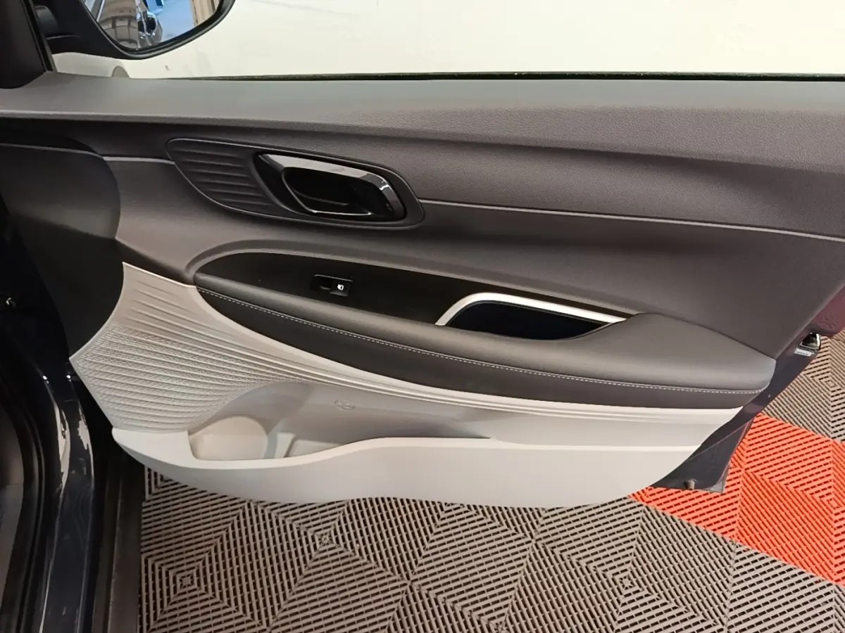 Vue rapprochée de la porte avant gauche de la Hyundai Bayon gris foncé, montrant le panneau intérieur bicolore noir et beige.