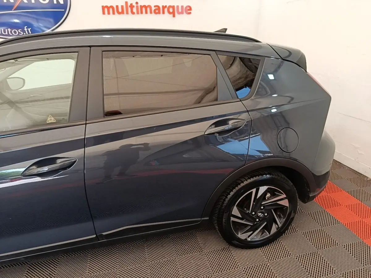 Vue latérale côté droit du Hyundai Bayon gris foncé, mettant en valeur la roue arrière et les lignes du coffre.