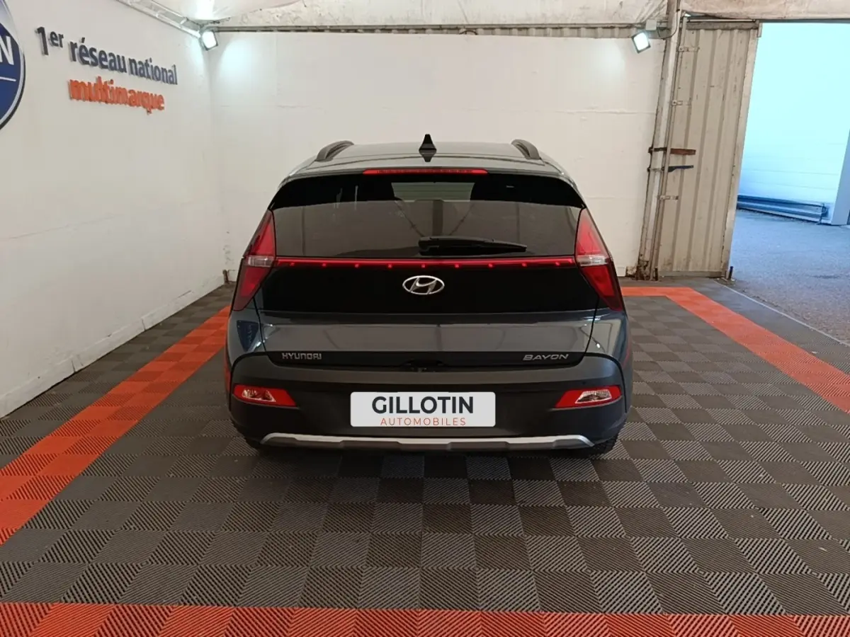 Vue arrière d'une Hyundai Bayon gris foncé 2023 avec feux arrière en bandeau lumineux et logo central visible.