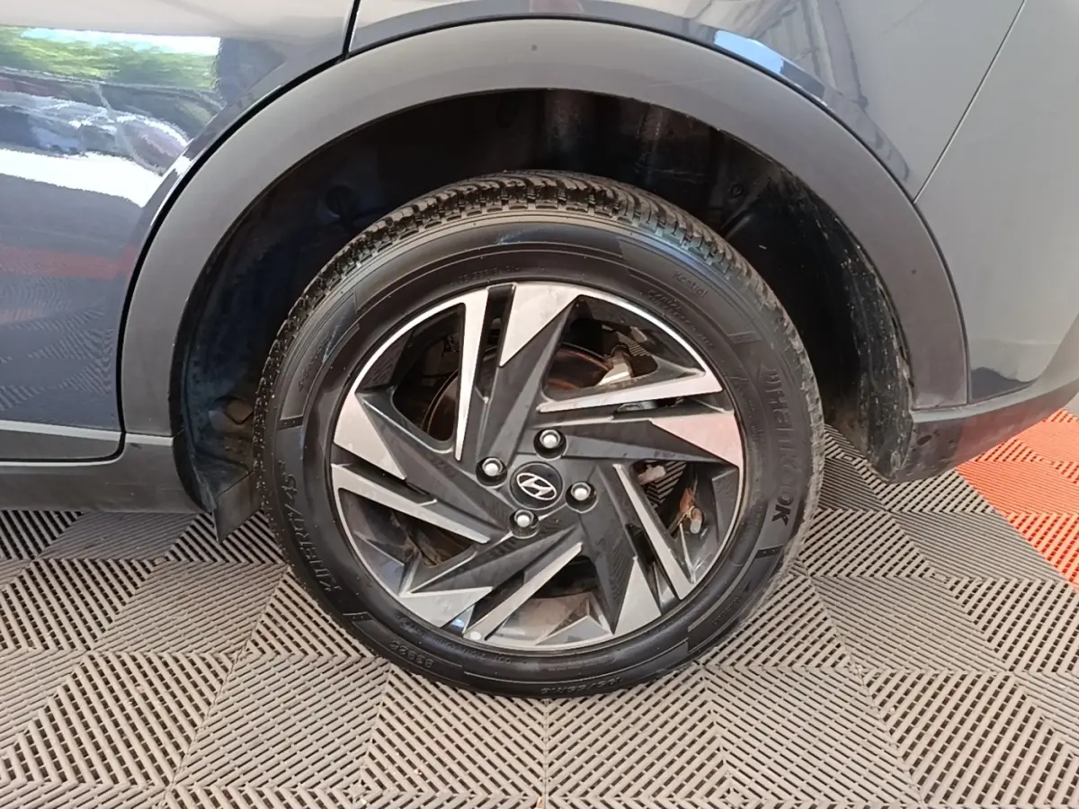 Gros plan sur la roue arrière droite d’une Hyundai Bayon gris foncé avec jante alliage au design géométrique.