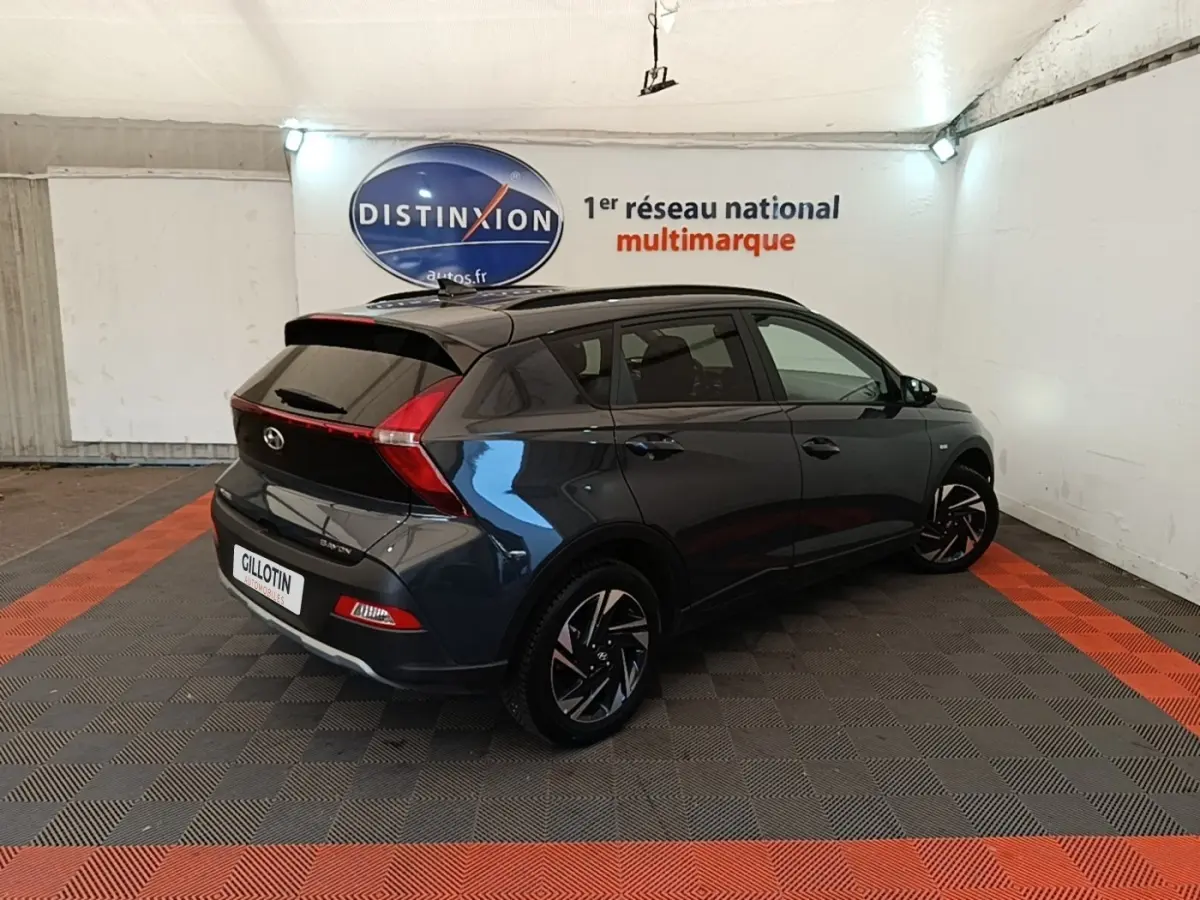 Vue 3/4 arrière droite d'une Hyundai Bayon gris foncé avec feux arrière en forme de boomerang et jantes noires stylisées.
