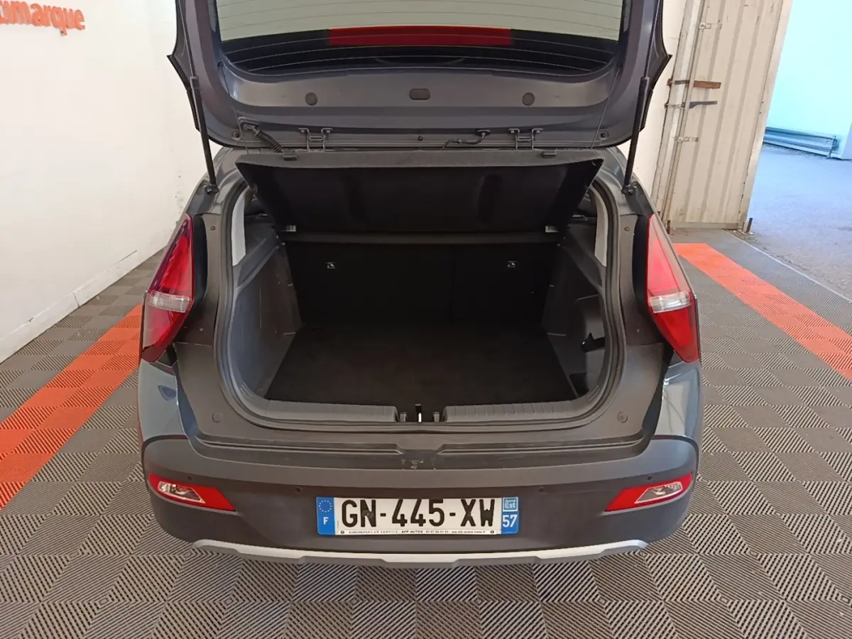 Vue arrière d’un Hyundai Bayon gris foncé avec coffre ouvert montrant l’espace de chargement vide.