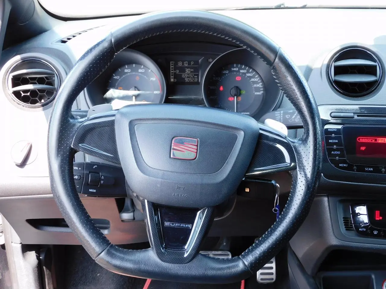 Volant cuir perforé avec logo SEAT et inscription CUPRA, tableau de bord et console centrale d'une Ibiza noire vue de face.