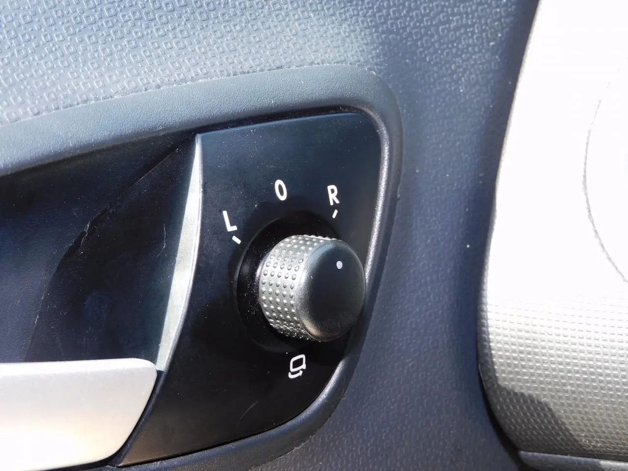 Gros plan sur le bouton de réglage des rétroviseurs côté conducteur de la SEAT Ibiza Cupra noire de 2011.