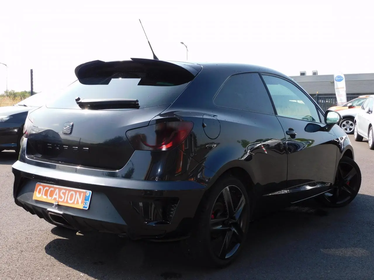 SEAT Ibiza Cupra noire vue 3/4 arrière droit, avec jantes noires et becquet de toit sportif.