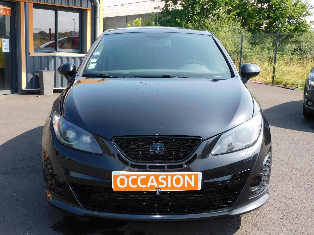Vue frontale d'une SEAT IBIZA Cupra noire avec calandre noire et plaque orange "OCCASION" visible.