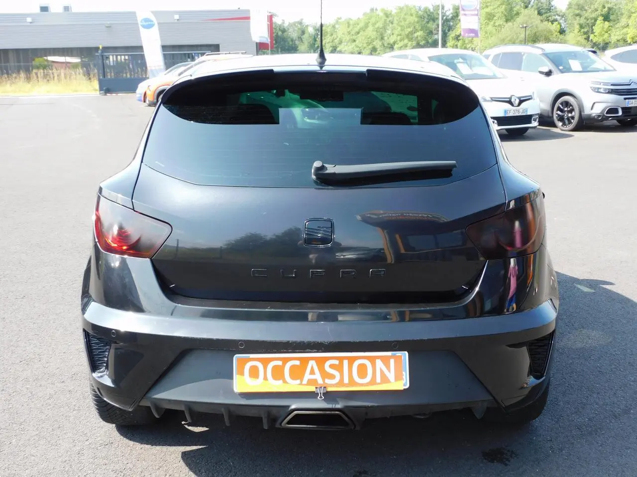 Vue arrière d'une SEAT Ibiza Cupra noire avec sigle CUPRA et sortie d'échappement centrale chromée sur parking.