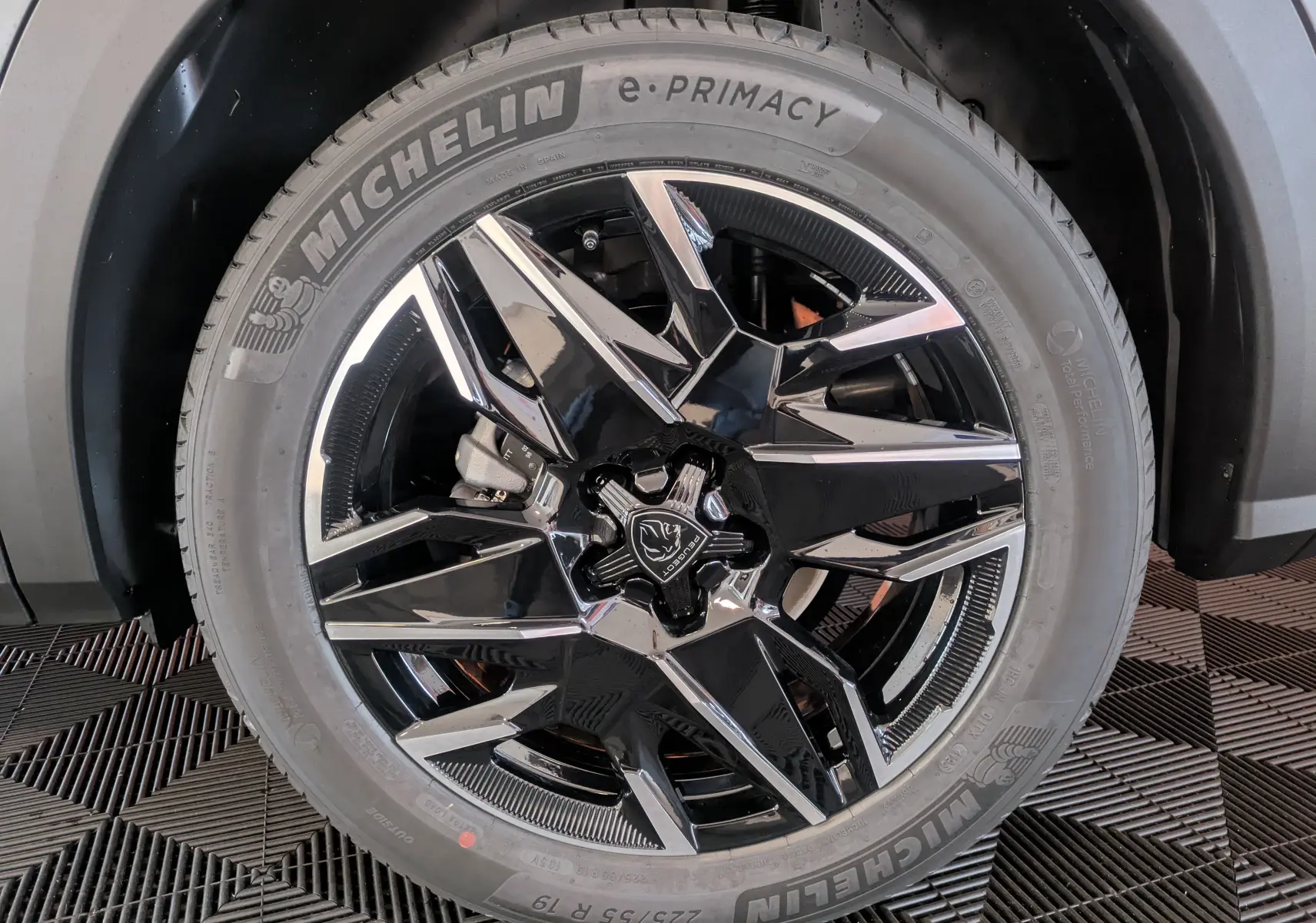 Gros plan sur la roue avant droite du Peugeot 3008 gris titanium, mettant en valeur la jante noire et argentée au design moderne.