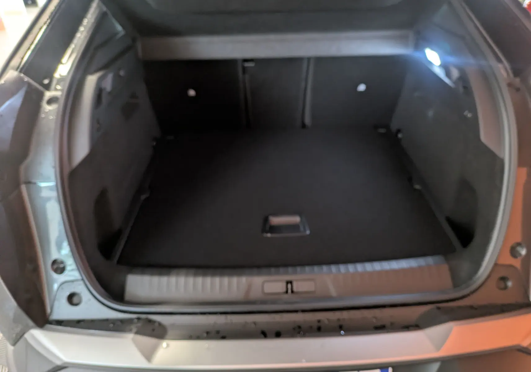 Coffre ouvert du Peugeot 3008 gris titanium, vue arrière montrant l’espace de chargement vide et éclairé.