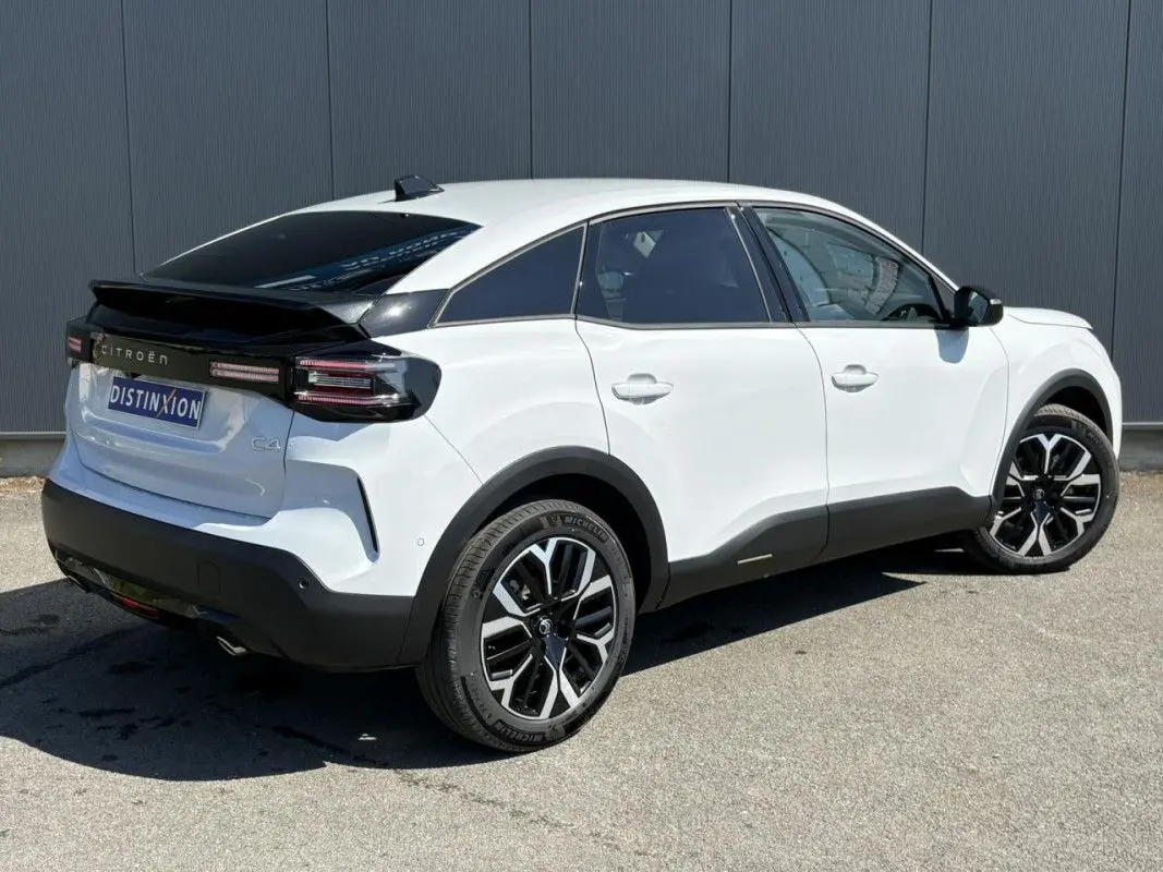 Vue 3/4 arrière droite d'une Citroën C4 blanche Okenite avec toit noir et jantes bicolores 18 pouces.