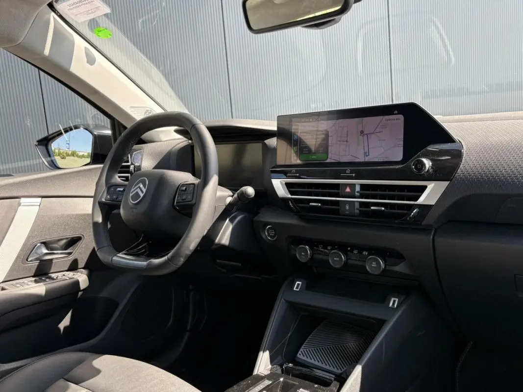 Vue intérieure côté conducteur du Citroën C4 blanc Okenite 2025, avec tableau de bord numérique et écran tactile central.