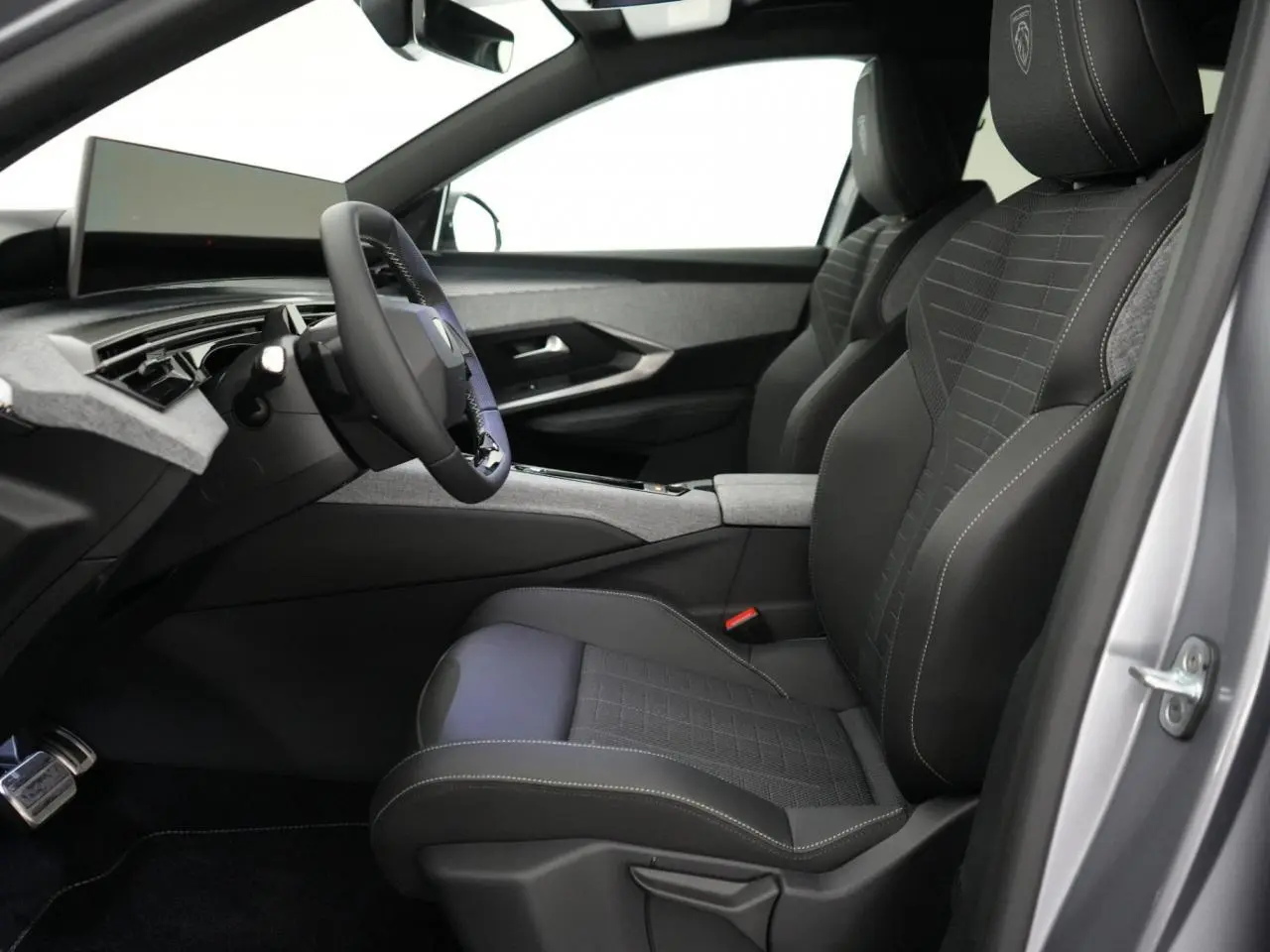 Vue intérieure côté conducteur du Peugeot 3008 gris Artense 2026, sièges noirs avec surpiqûres blanches et tableau de bord moderne.