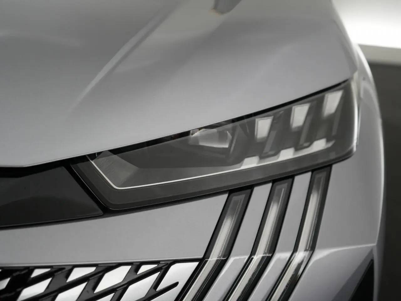 Gros plan sur le phare avant droit du Peugeot 3008 gris Artense, mettant en valeur les feux LED en forme de griffes.