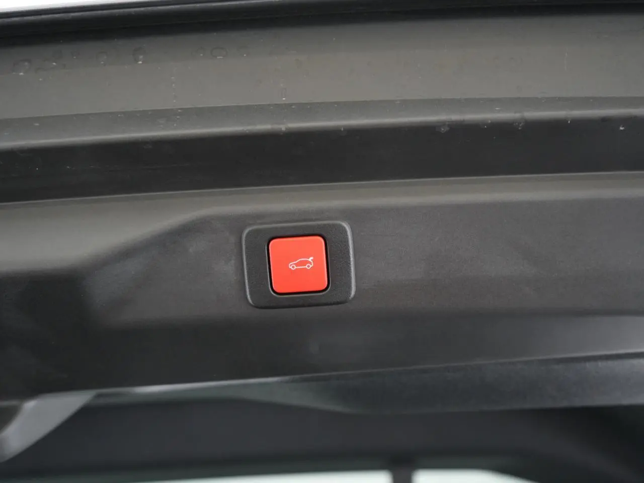 Bouton rouge d'ouverture électrique du hayon visible à l'intérieur du coffre du Peugeot 3008 gris Artense 2026.