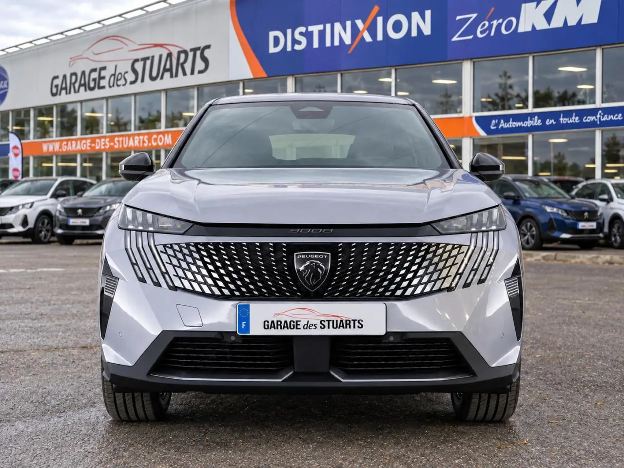 Vue avant d'un Peugeot 3008 gris Artense avec calandre noire à motif géométrique et phares LED fins, sur parking de concession.
