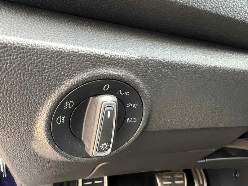 Gros plan sur le bouton de commande des phares du Volkswagen T-Roc gris, intérieur côté conducteur.