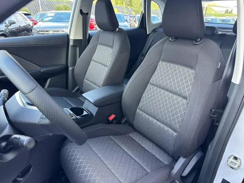 Vue intérieure côté gauche des sièges avant en tissu noir du MG ZS Hybrid+ 2025 avec accoudoir central et volant cuir.