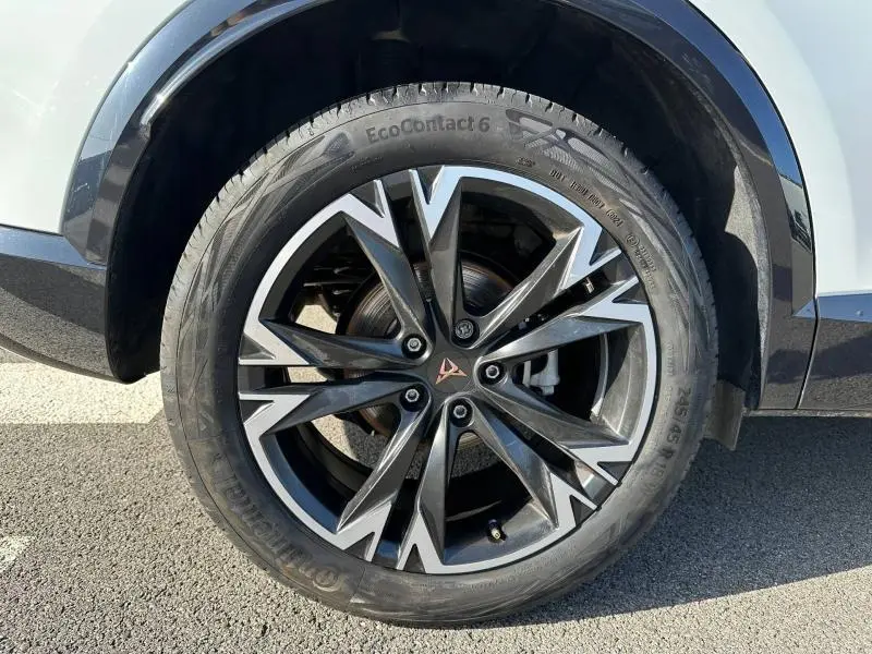 Gros plan sur la roue avant droite du CUPRA Formentor blanc Nevada métallisé avec jante alliage noire et argentée au design anguleux.