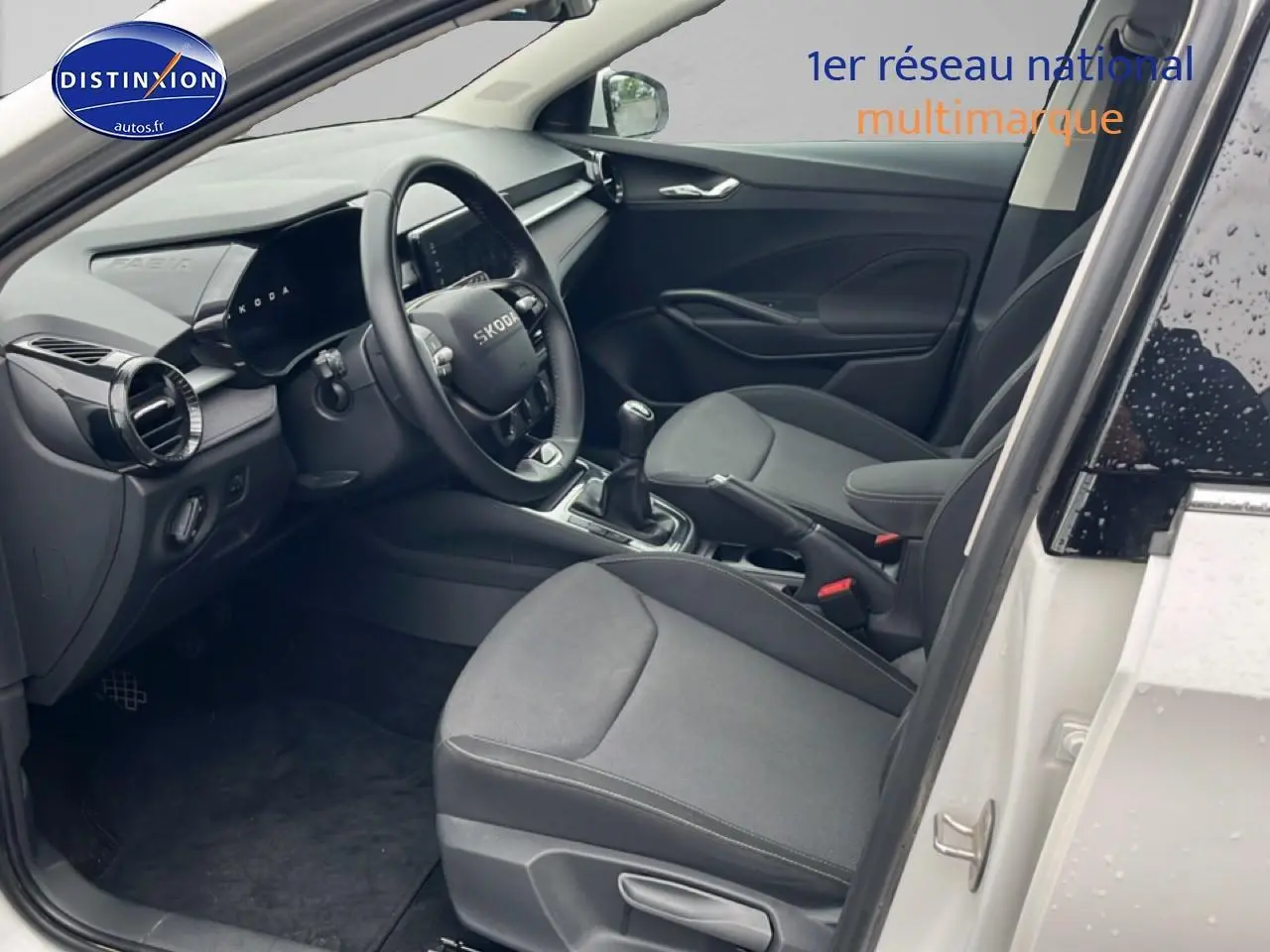 Intérieur de la Skoda Fabia blanc, vue côté conducteur avec volant cuir et boîte manuelle visible.