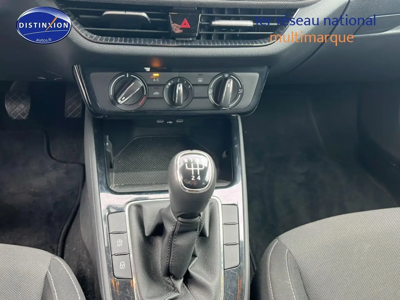 Vue rapprochée de la console centrale d’une Skoda Fabia blanche 2025 avec levier de vitesse manuel et commandes climatisation.