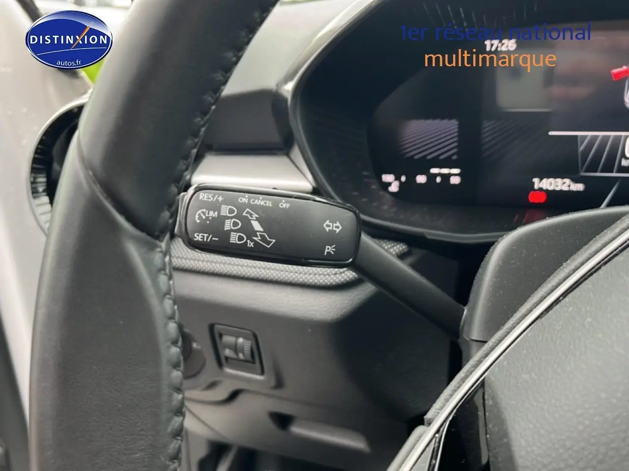 Gros plan sur la commande de régulateur de vitesse à gauche du volant cuir d'une Skoda Fabia blanche, tableau de bord numérique visible.