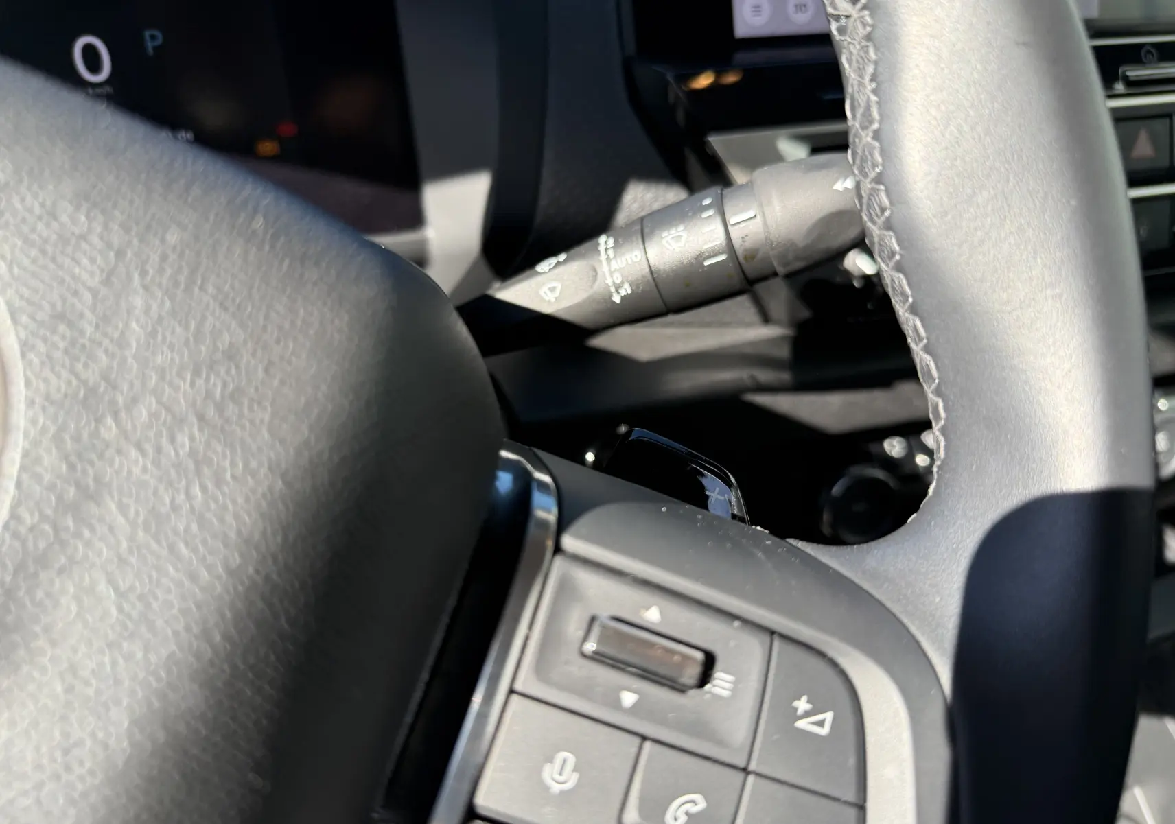 Gros plan intérieur sur le volant en cuir noir de la Citroën C4 Hybrid 2025, avec commandes audio et régulateur visibles.