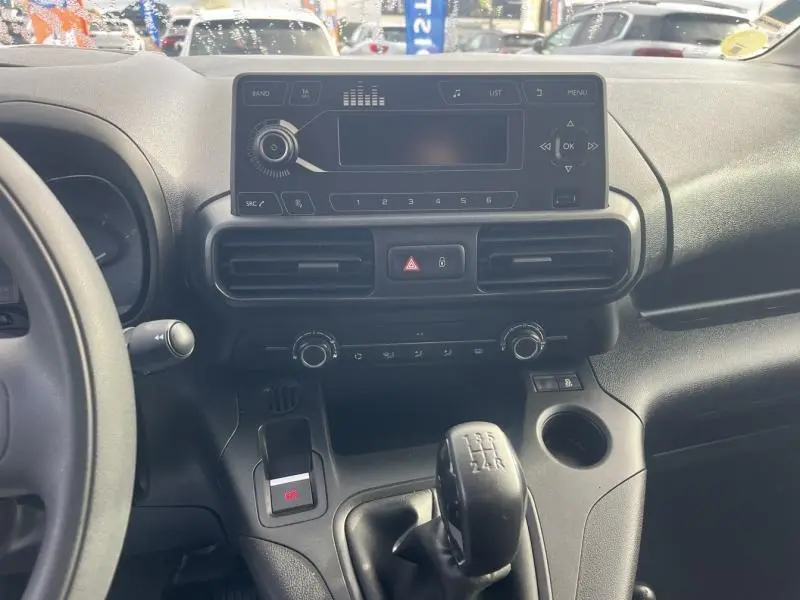 Vue rapprochée de la console centrale noire du Citroën Berlingo Fourgon blanc, avec levier de vitesses manuel et écran multifonction.