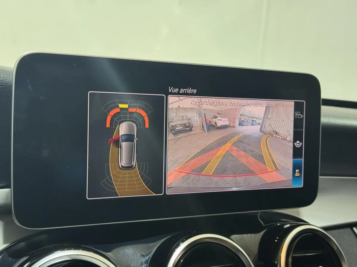 Écran central de la Mercedes Classe C Break noir 2019 montrant la caméra de recul et l'aide au stationnement active.