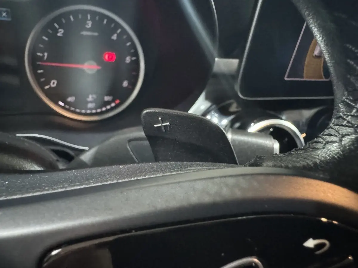 Gros plan sur la palette de changement de vitesse droite et le compte-tours du tableau de bord d'un Mercedes Classe C Break noir 2019.