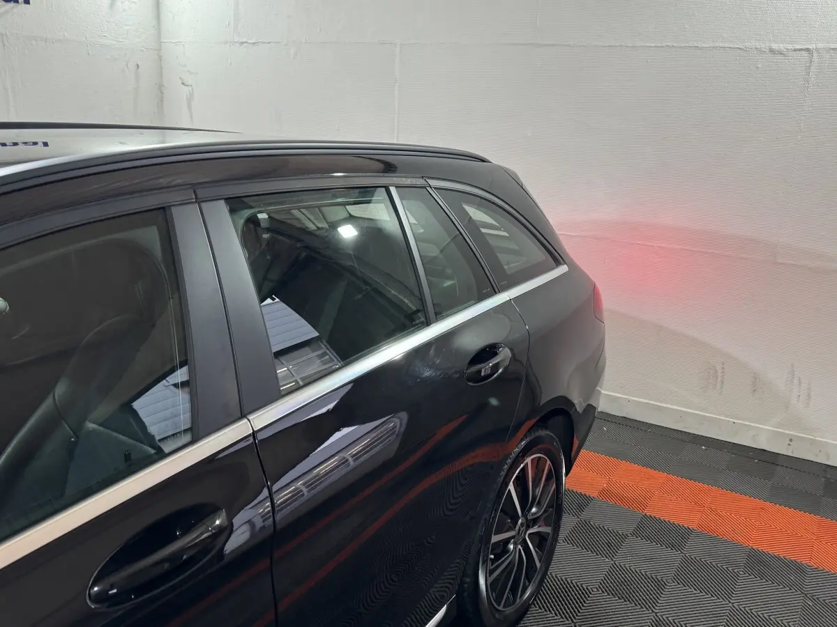 Vue latérale arrière droite d'une Mercedes Classe C Break C 200 d Business Line noire avec jantes alliage et feux arrière allumés.