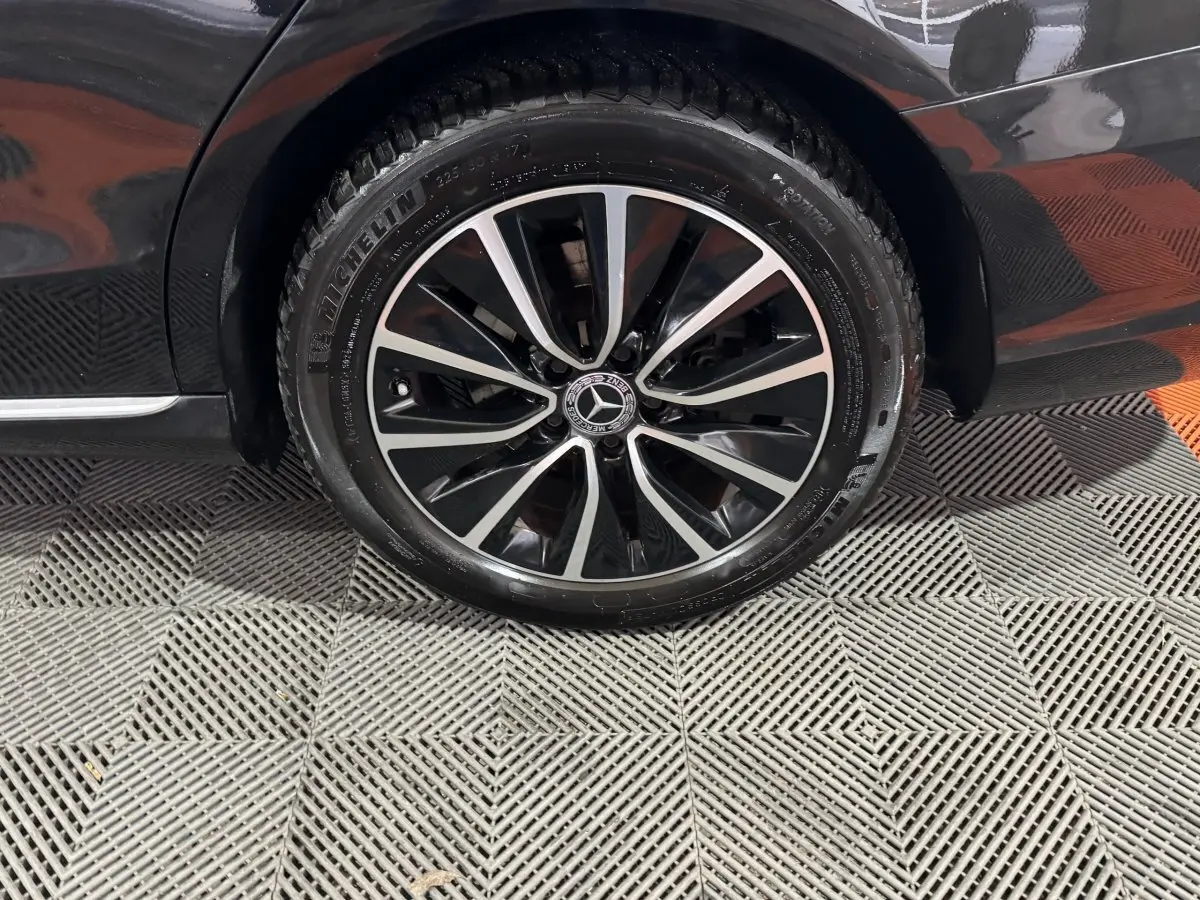 Gros plan sur la roue avant gauche noire d'un Mercedes Classe C Break C 200 d Business Line 2019 avec jante alliage bicolore.