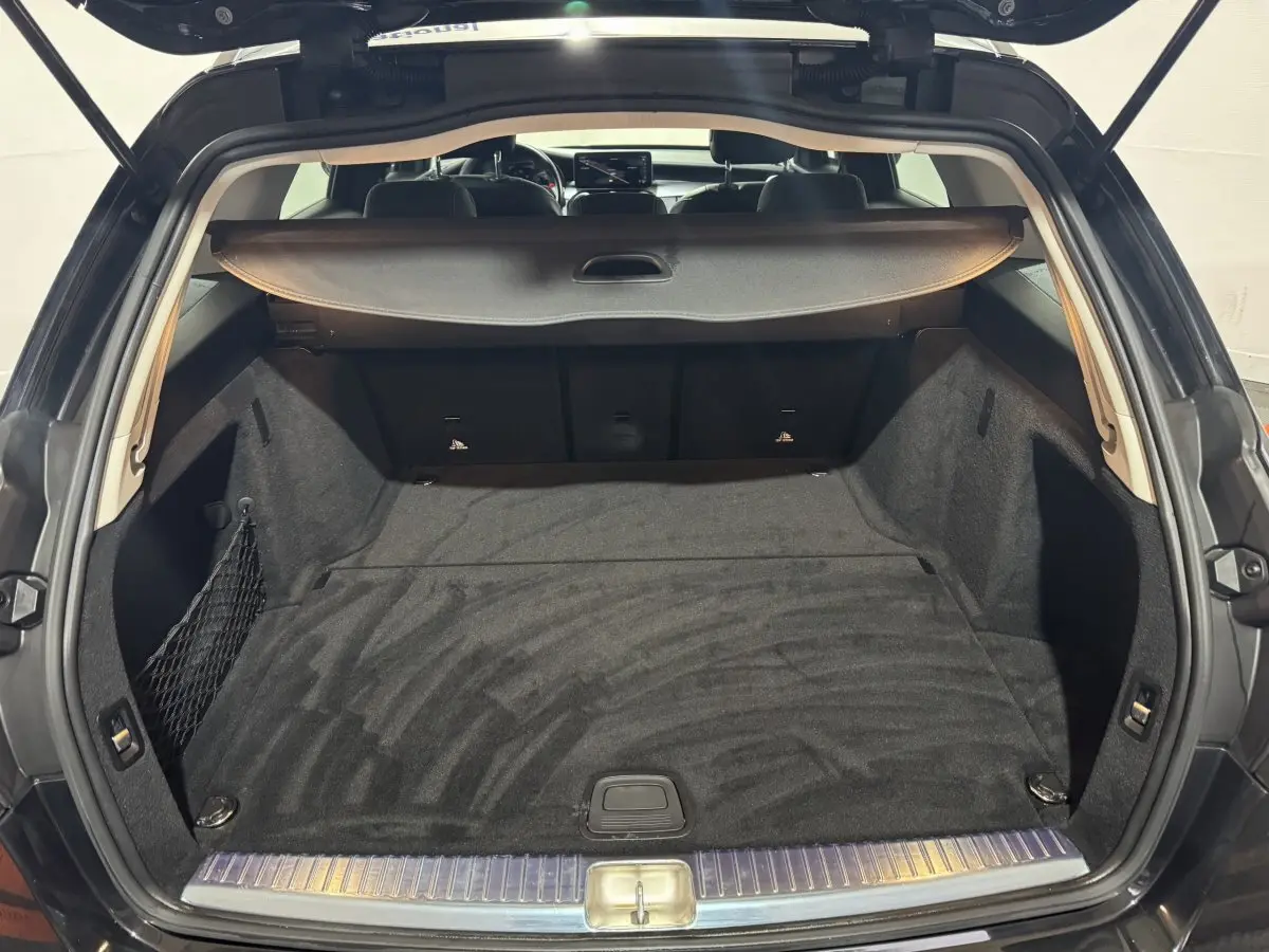 Coffre spacieux noir ouvert d'une Mercedes Classe C Break C 200 d Business Line vue de l'arrière avec cache-bagages déployé.