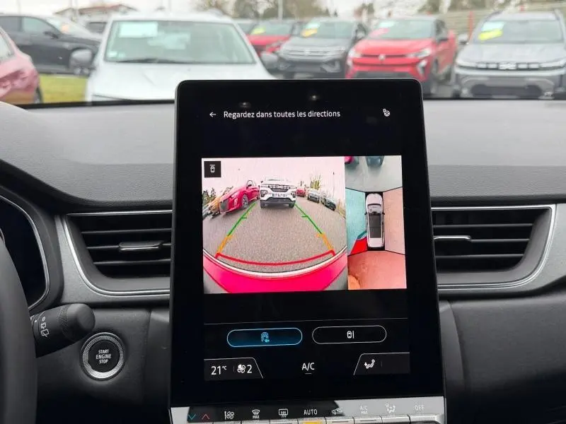 Vue intérieure du tableau de bord du Renault Captur 2025 rouge, écran central affichant la caméra de recul avec vue arrière et vue 360° du véhicule.