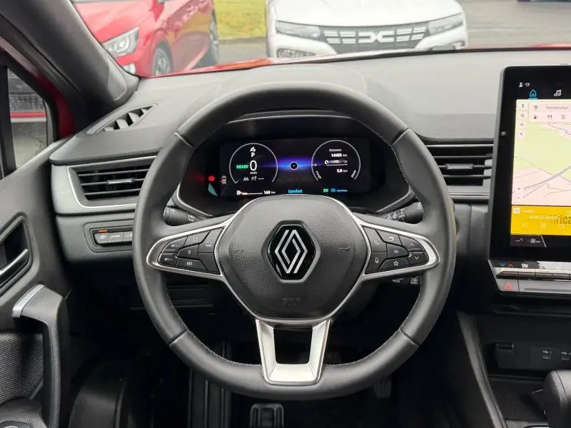 Vue intérieure centrée sur le volant du Renault Captur 2025 rouge, avec tableau de bord numérique et écran tactile.