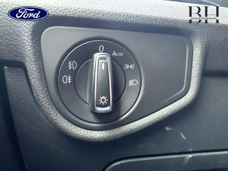 Commande des phares en gros plan sur tableau de bord noir, avec logo Ford visible en haut à gauche.