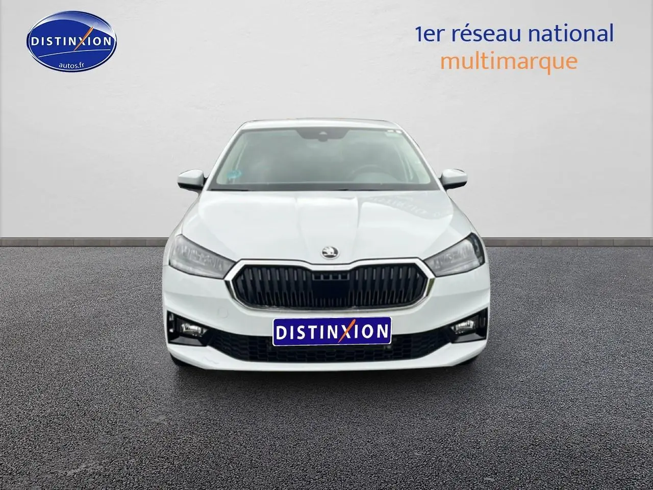 Vue frontale d'une Skoda Fabia blanche 2025 avec calandre noire et phares LED, sur fond neutre gris.