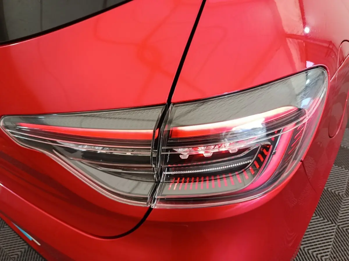 Gros plan sur le feu arrière droit rouge et transparent d'une Renault Clio Techno TCe 90 2024 rouge.