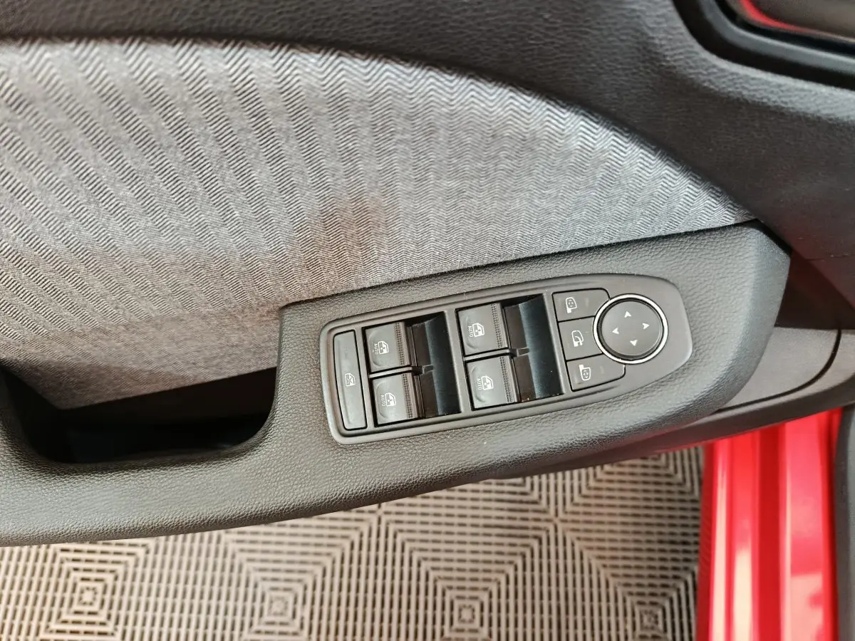 Commande des vitres et rétroviseurs sur la porte côté conducteur d'une Renault Clio Techno TCe 90 rouge 2024.