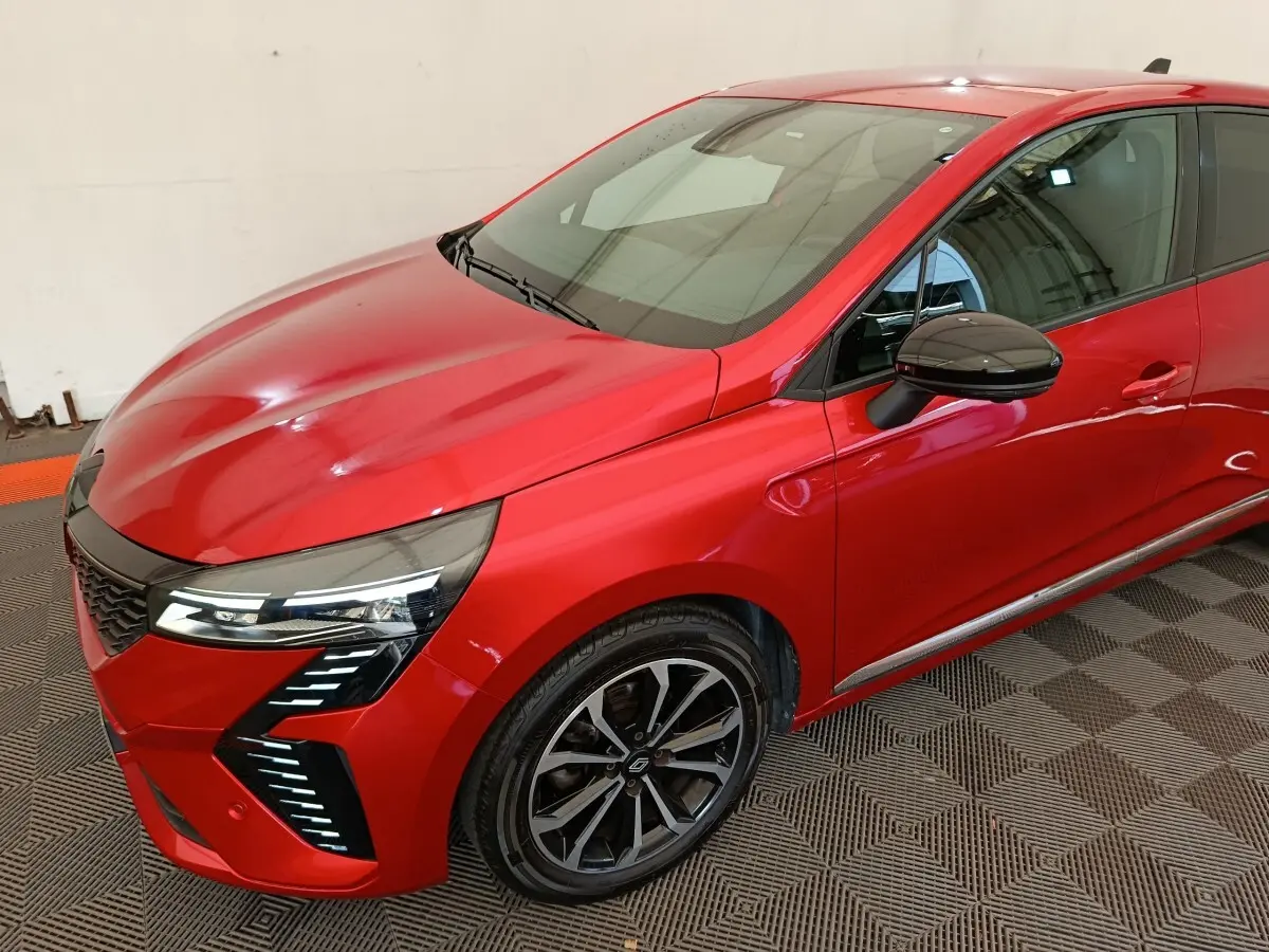 Vue 3/4 avant droite d'une Renault Clio Techno TCe 90 rouge avec phares LED et jantes alliage noires.