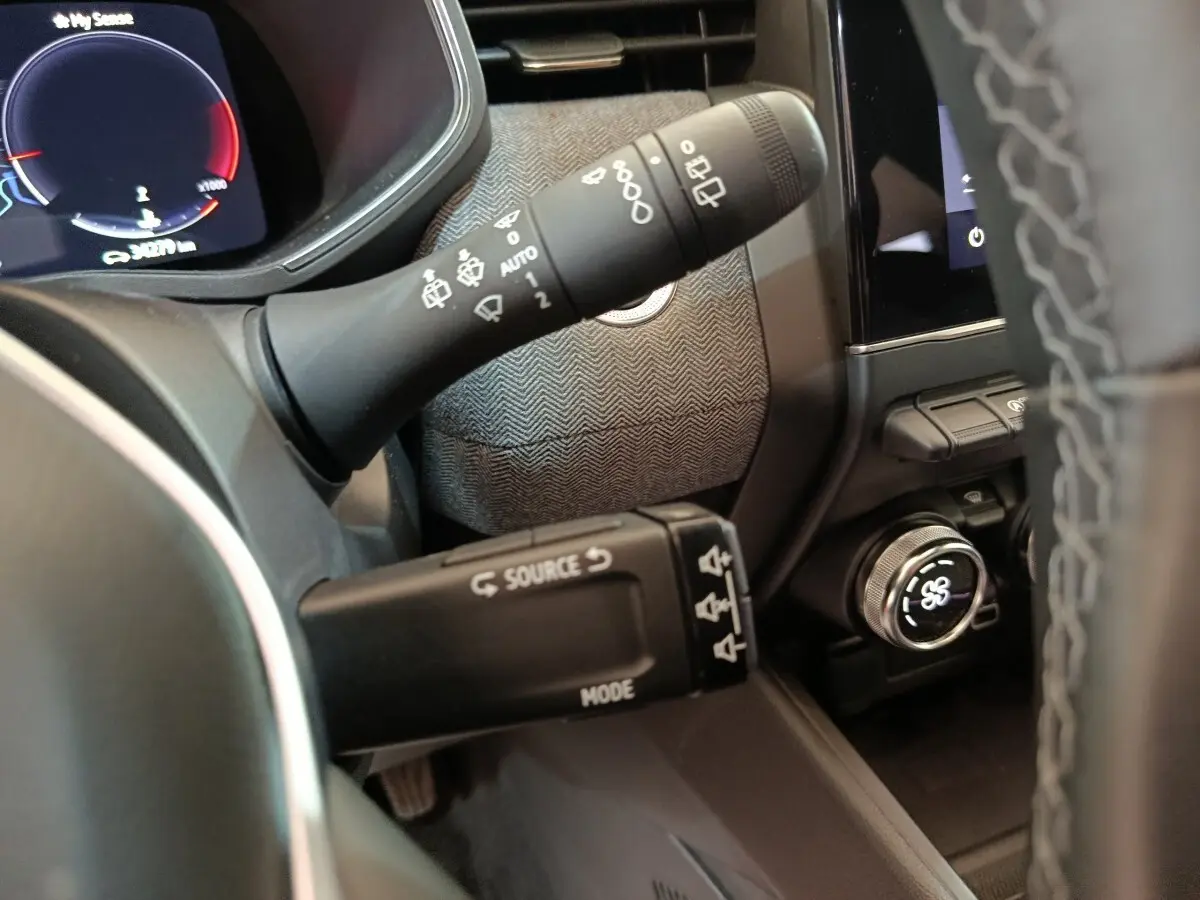 Gros plan sur les commandes de volant et tableau de bord numérique de la Renault Clio Techno TCe 90 rouge 2024.