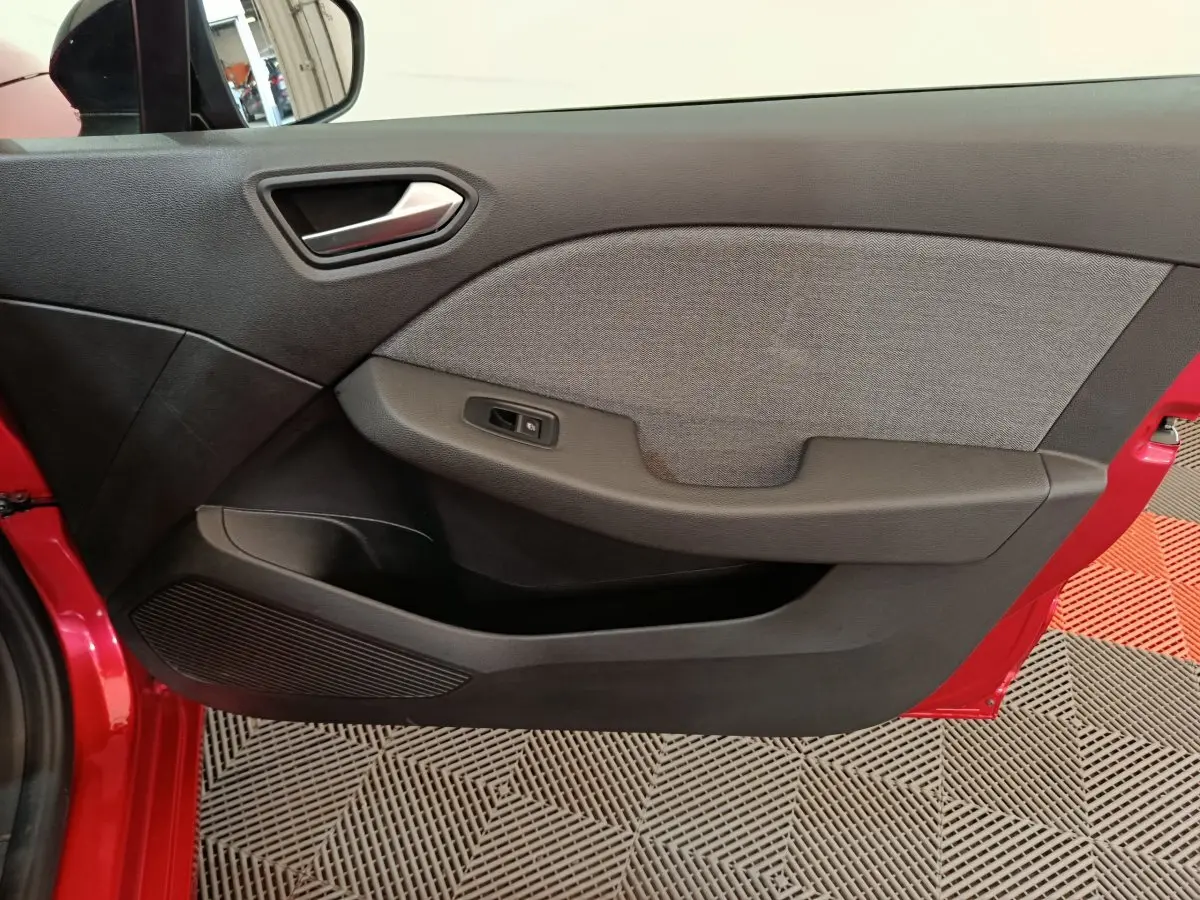 Vue rapprochée de la porte avant gauche rouge de la Renault Clio 2024 avec garniture noire et grise.