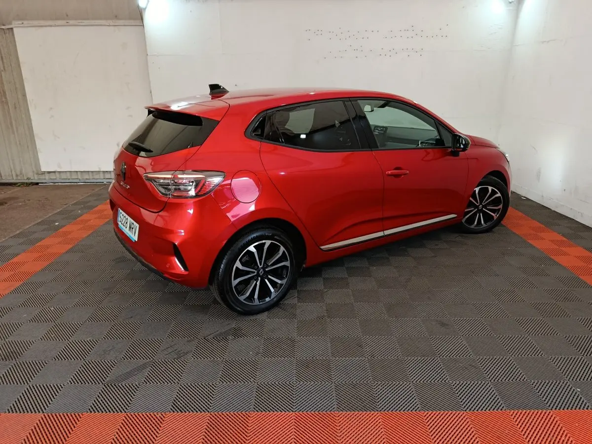 Renault Clio Techno TCe 90 rouge vue 3/4 arrière droit, jantes alliage noires et vitres teintées.