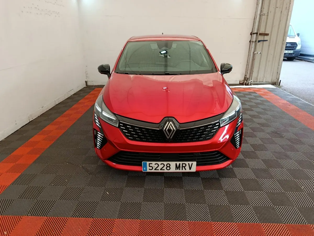 Vue frontale d'une Renault Clio rouge 2024 avec calandre noire et phares LED distinctifs dans un garage.