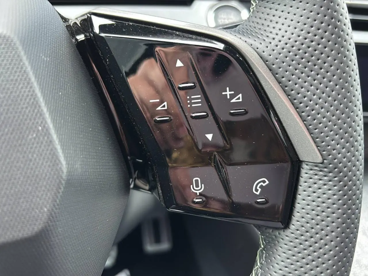 Gros plan sur les commandes noires brillantes au volant du Peugeot 3008 Hybrid 2026, côté gauche, avec boutons multifonctions.