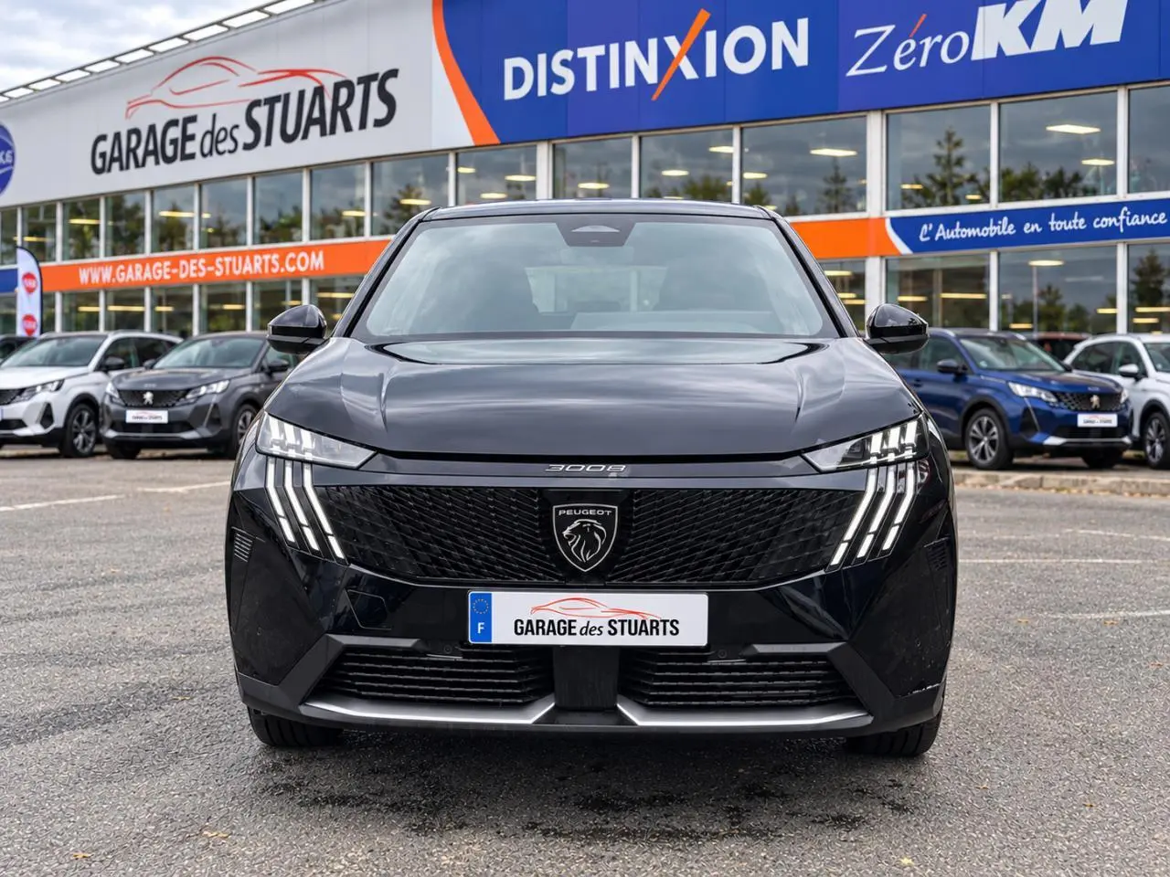 Vue avant d’un Peugeot 3008 noir Perla avec calandre noire et feux LED à griffes distinctifs, stationné devant un garage.