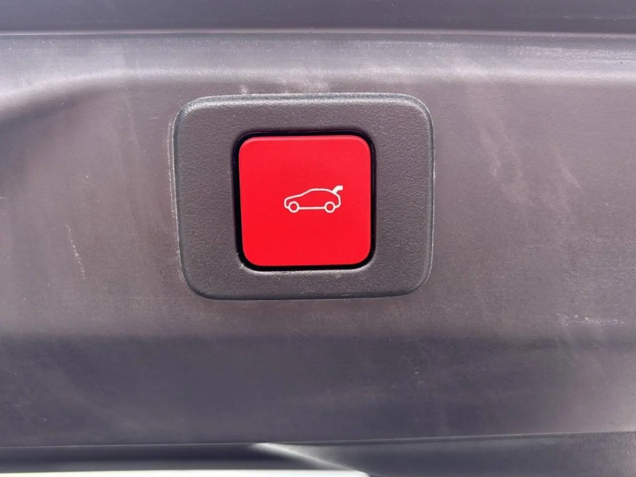 Bouton rouge d'ouverture électrique du hayon sur le coffre d'un Peugeot 3008 noir Perla.