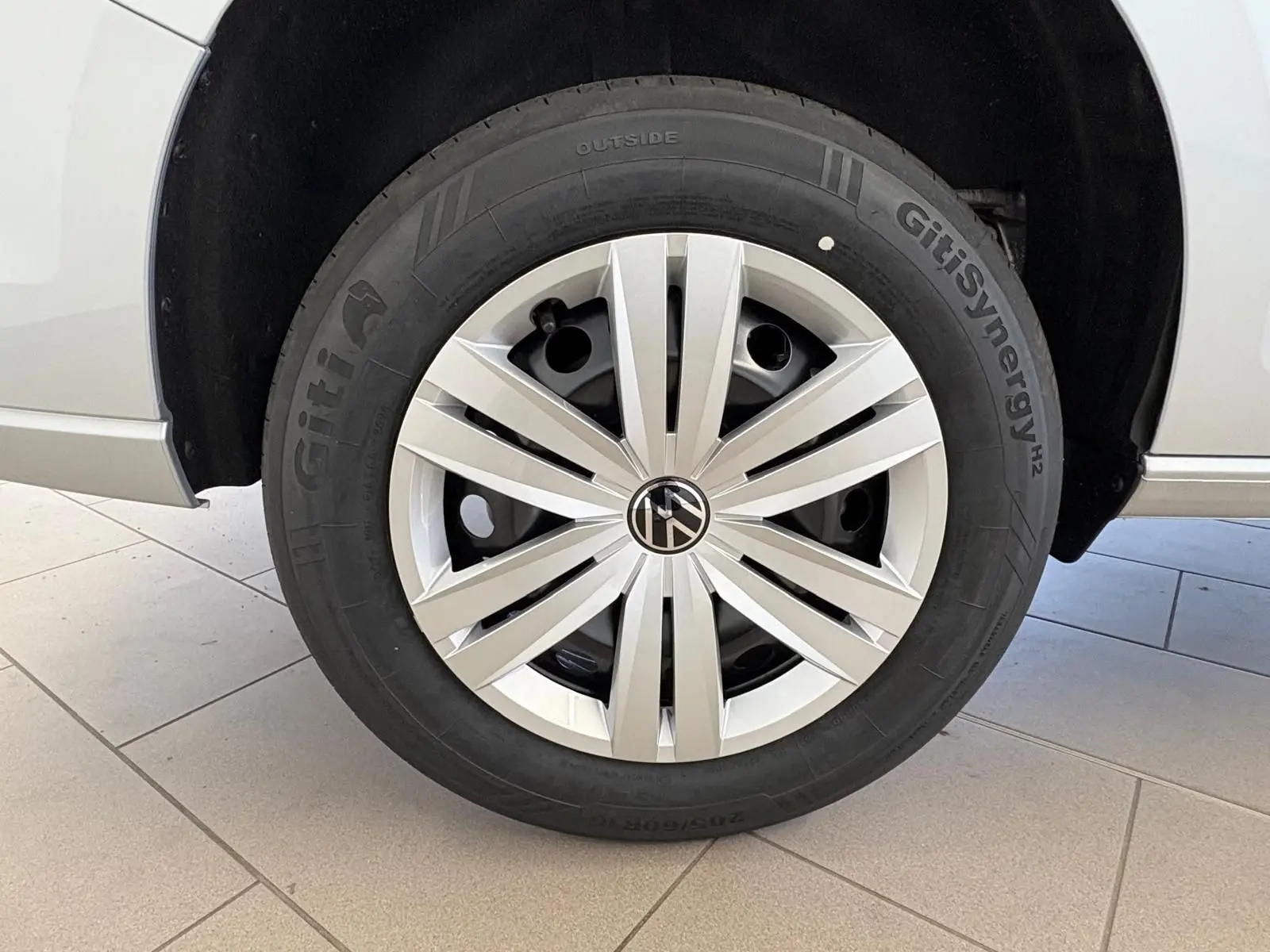 Gros plan sur la roue avant droite du Volkswagen Caddy gris argent 2025 avec jante en alliage et pneu GitiSynergy.