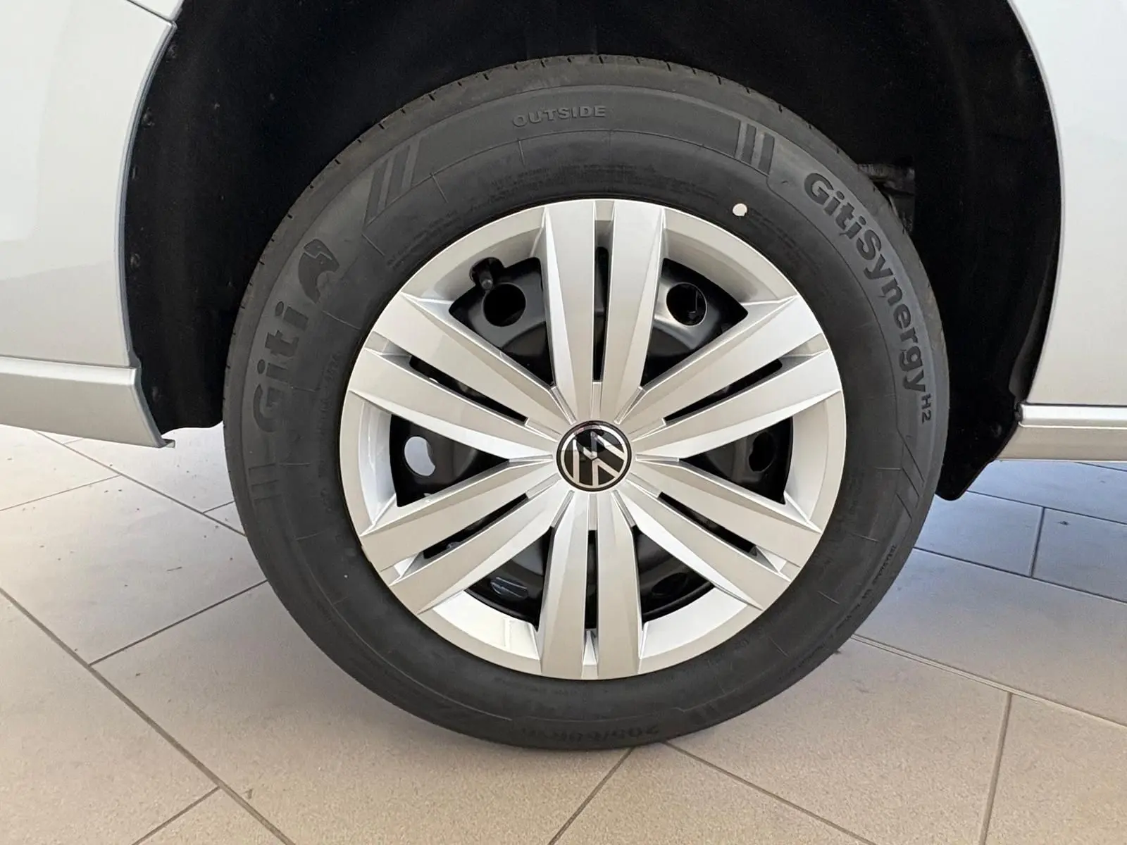 Gros plan sur la roue avant gauche gris argent du Volkswagen Caddy 2025 avec jante à enjoliveur moderne.