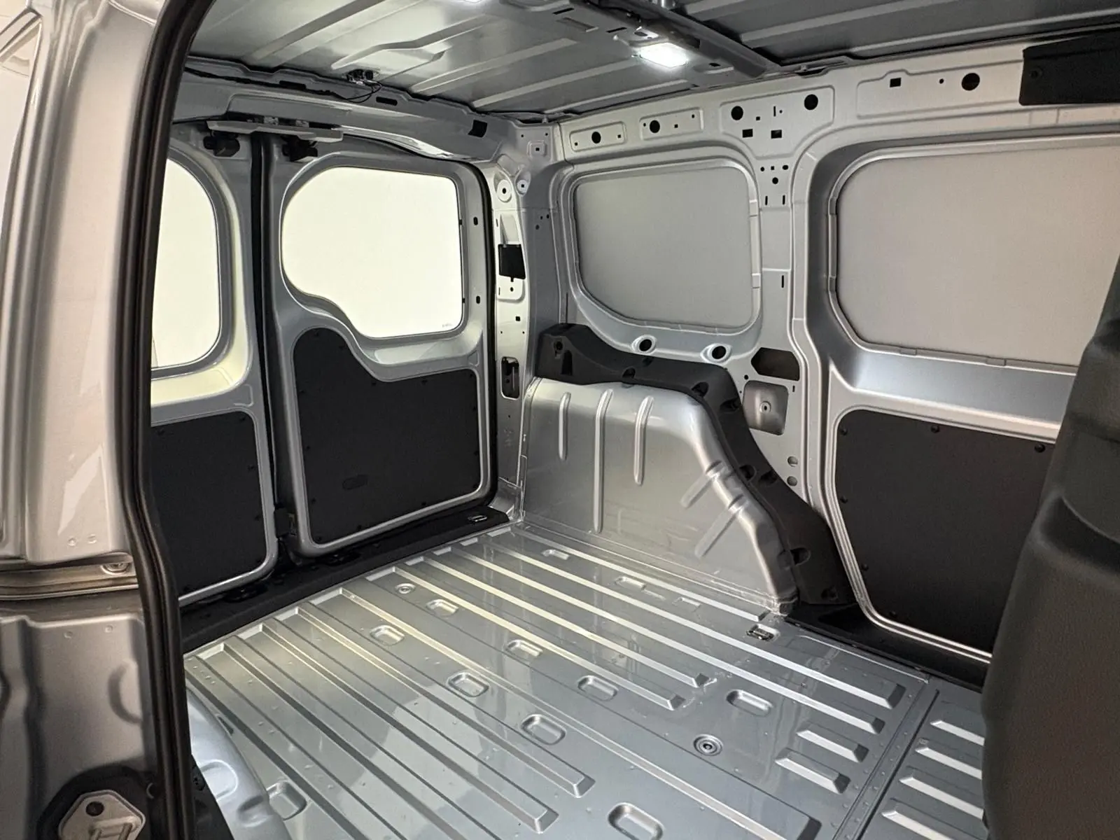 Intérieur de la zone de chargement du Volkswagen Caddy 2025 gris argent, vue depuis l'ouverture latérale droite.