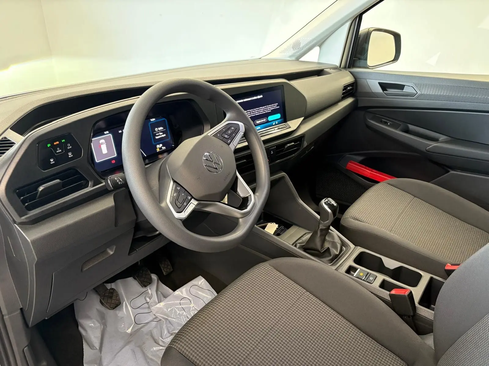 Intérieur du Volkswagen Caddy 2025 vu côté conducteur, tableau de bord moderne et levier de vitesse manuel gris argent.